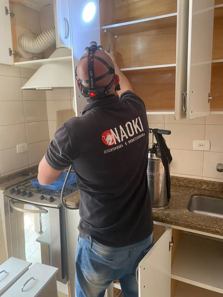 Técnico uniformizado da Naoki aplicando tratamento em cozinha de apartamento